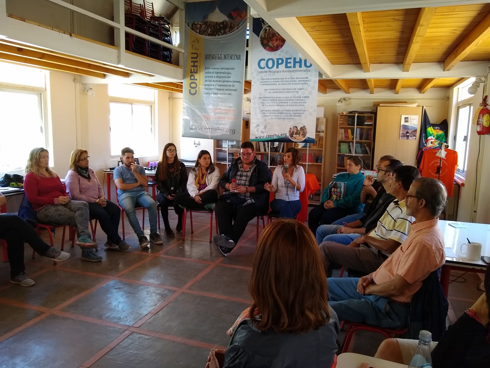 Grupo de adultos sentados en círculo durante un encuentro de COPEHU, conversando en una sala luminosa.